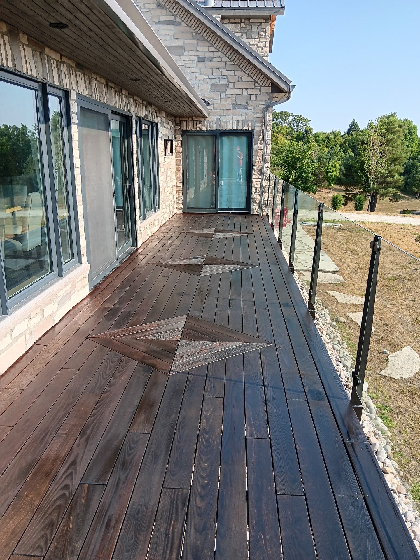 After deck staining: rich dark brown stained deck with geometric pattern and enhanced protection