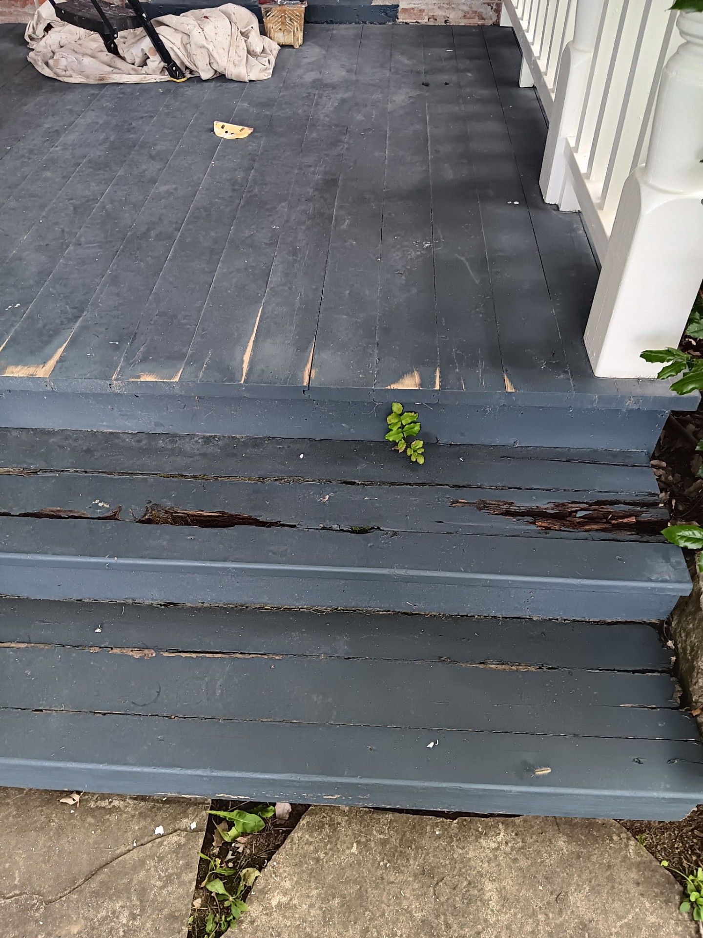 Before porch repair and paint: worn, peeling gray deck boards showing damage